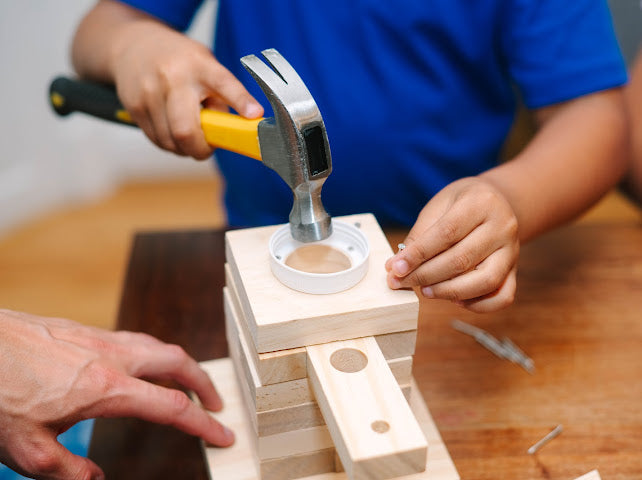 Child hammering nails in SparkJump woodworking kit, real tools real wood Australia.