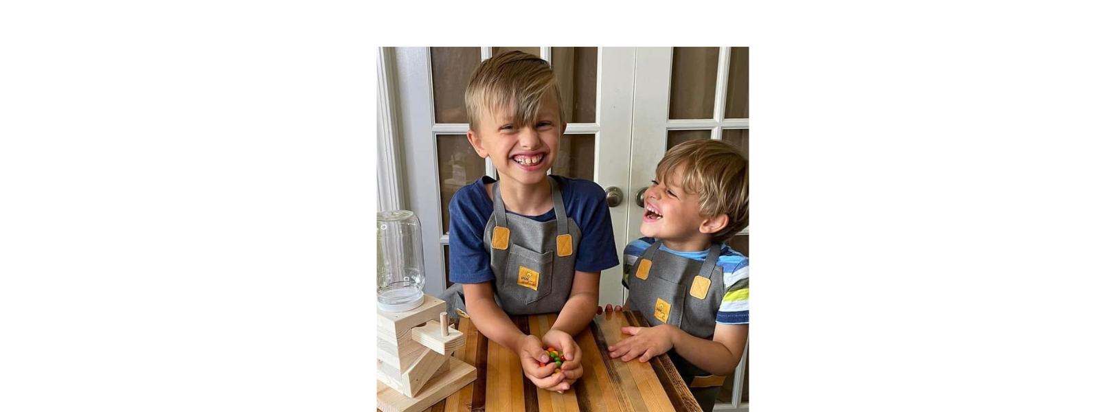 Two children wearing SparkJump aprons, building woodworking kits together, SparkJump Australia